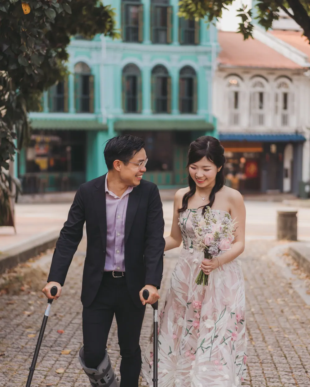 Jingwen and Thai walking together down a street of colourful Singapore shophouses